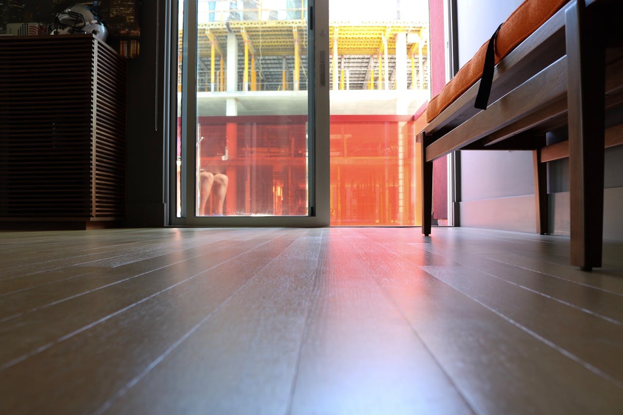 Interior view highlighting modern hardwood flooring and sunlight streaming through a glass door.